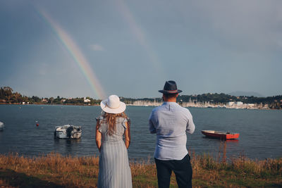 A woman and a man watching sea and rainbow