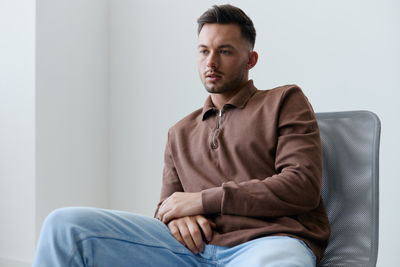 Portrait of young man sitting on sofa at home