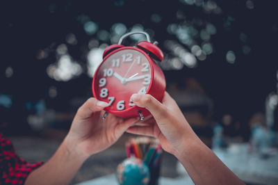 Close-up of hand holding red rose outdoors