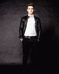 Portrait of young man standing against black background