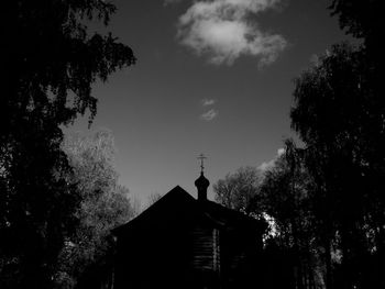 Low angle view of silhouette trees and building against sky