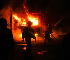 Rear view of silhouette people against burning building