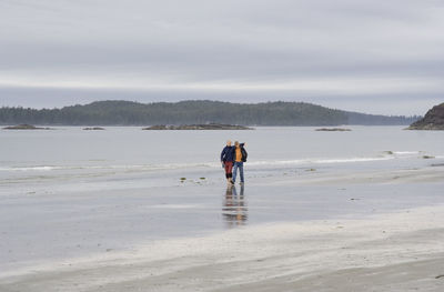 People on beach against sky during winter