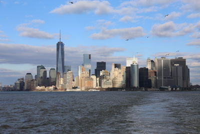 Sea by modern buildings against sky in city