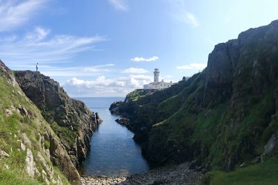 Scenic view of sea by mountains against sky