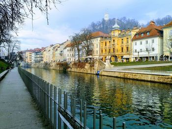 Bridge over river amidst buildings in city against sky