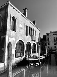 Boats moored in canal by building against sky
