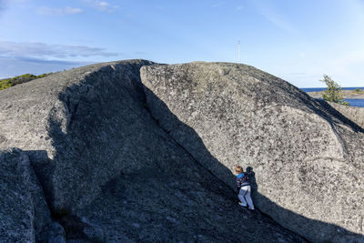 Boy climbing on rock, hallskar, sweden