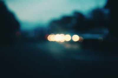 Defocused image of illuminated lights on street at night