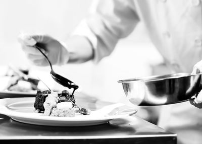 Midsection of man preparing food in plate on table