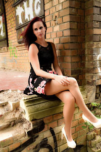 Young woman sitting against wall