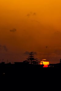 Silhouette car against orange sky during sunset