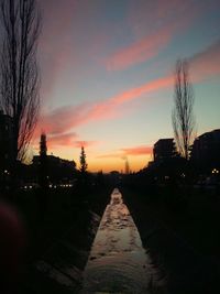 Road passing through city at sunset