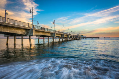 Bridge over sea against sky during sunset