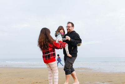 Family, a father and three kids playing on sandy beach together