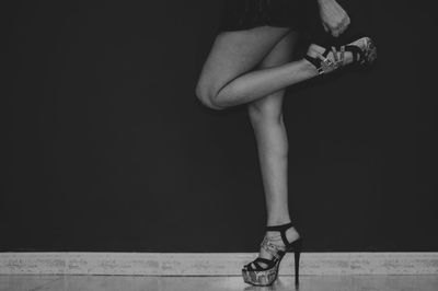 Low section of woman in high heels against black background