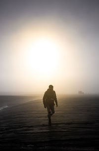 Rear view of man standing on land against sky