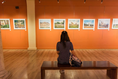 Rear view of woman sitting on wooden floor