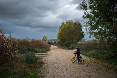 Man riding bicycle on field against sky