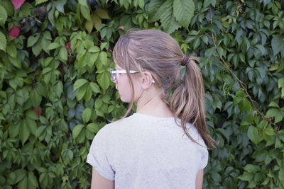 Rear view of girl standing by plants in park