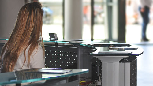 Rear view of woman using laptop on table