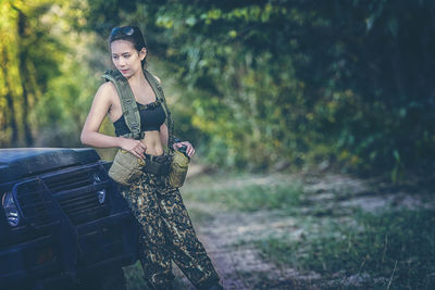 Portrait of young woman standing against trees