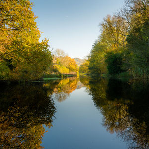 Reflection of trees in canal against sky during autumn