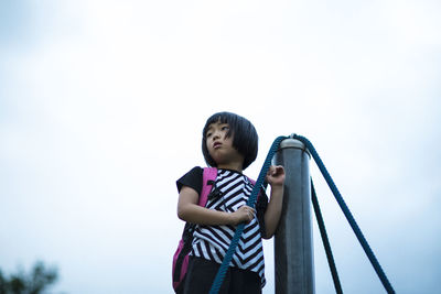 Low angle view of cute backpack girl standing against clear sky