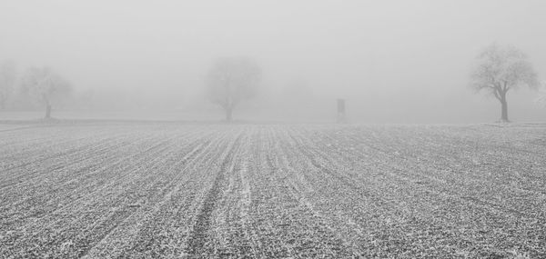 Snow covered field against sky during foggy weather