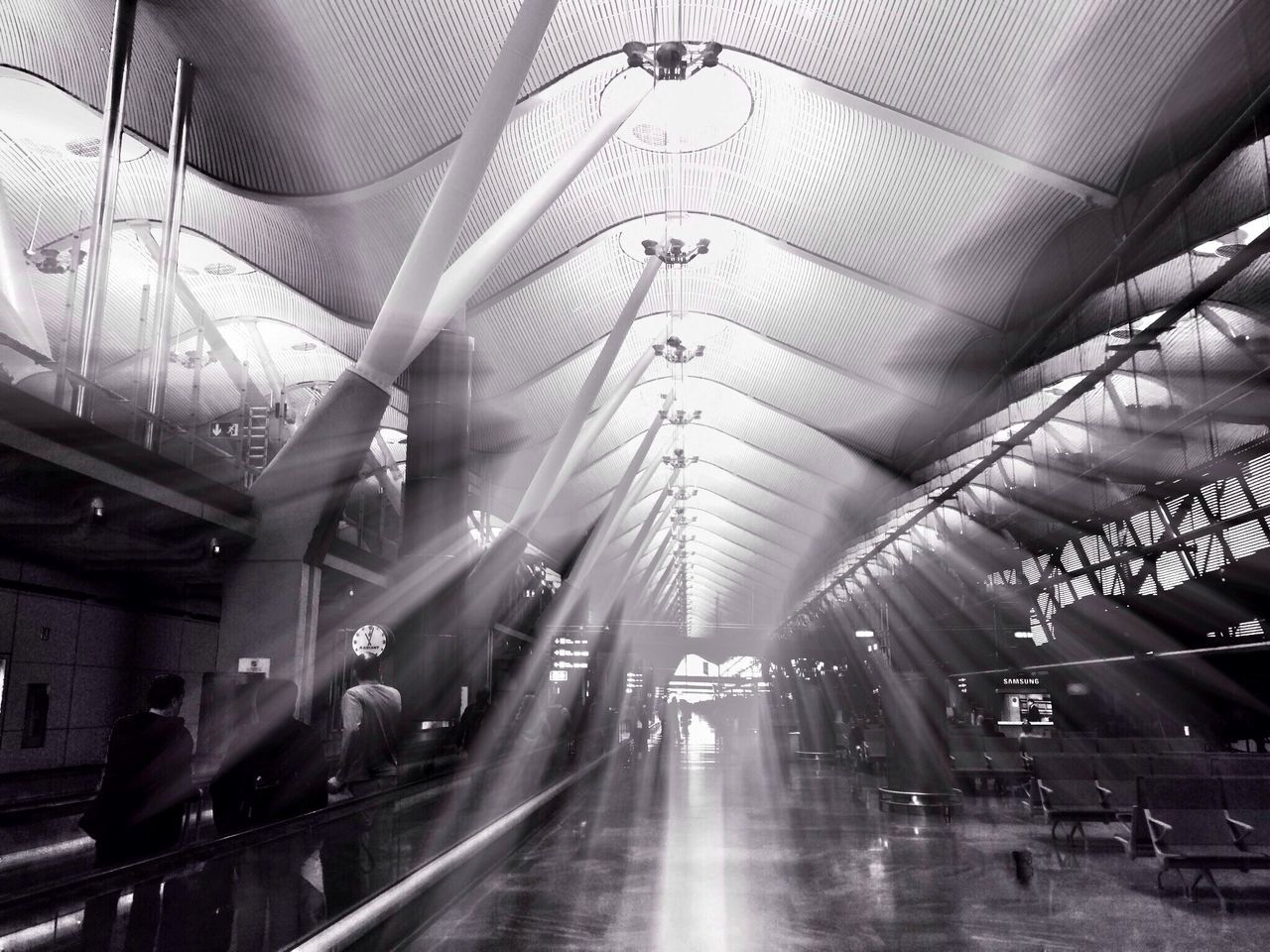 indoors, ceiling, built structure, architecture, illuminated, the way forward, transportation, lighting equipment, incidental people, diminishing perspective, modern, city life, night, city, interior, vanishing point, travel, building exterior, reflection, architectural column