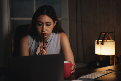 Young woman using laptop on table at home