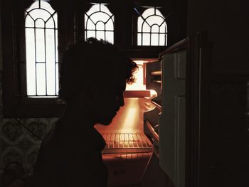 Portrait of woman looking at illuminated window at home
