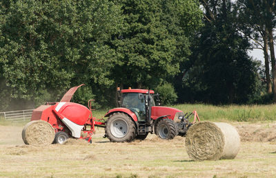 Tractor by hay bale on agricultural field