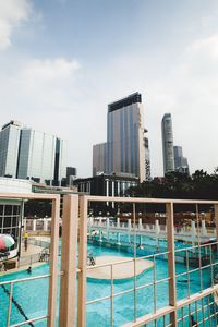 Buildings by swimming pool in city against sky