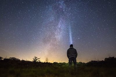 Rear view of man with illuminated headlamp against star field