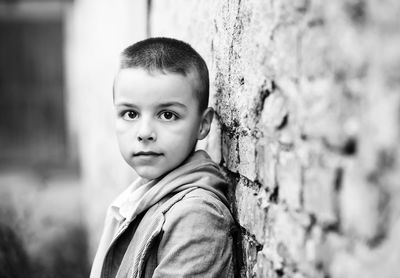 Portrait of cute boy standing against wall