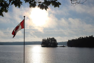 Scenic view of flag by lake against sky
