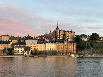 Buildings by river against sky