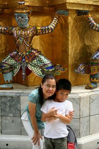 Portrait of happy boy standing against statue