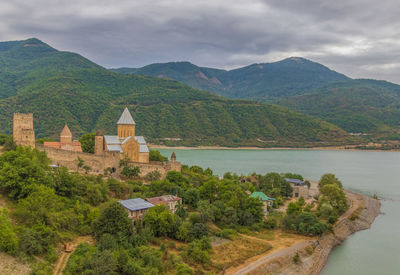 Scenic view of buildings and mountains against cloudy sky