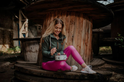 Young woman smiling while sitting on wood