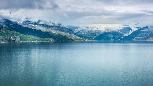 Scenic view of lake by snowcapped mountains against sky