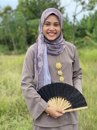 Portrait of smiling young woman standing on field celebrate eid fitr 2022