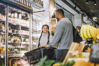 Smiling girl shopping for grocery with father at delicatessen