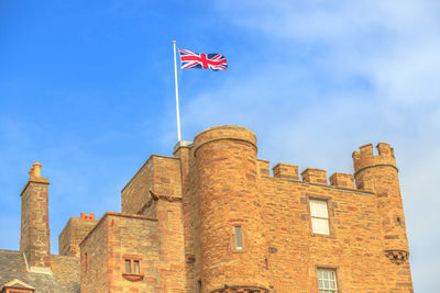 Low angle view of flag on building against sky