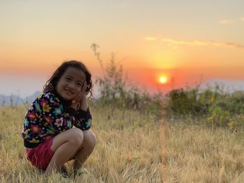 Portrait of girl on field against sky during sunset