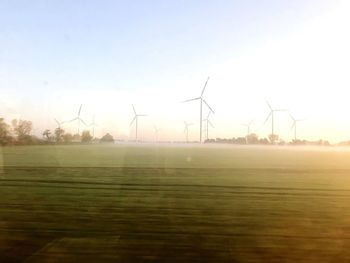 Wind turbines on field against sky