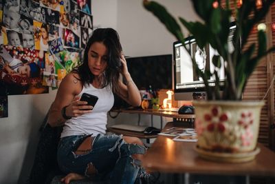 Young woman using phone while sitting on table