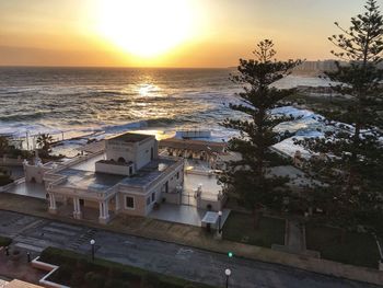 Scenic view of sea by buildings against sky during sunset