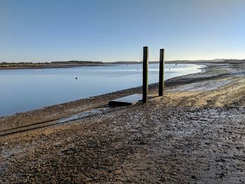 Wooden posts on beach against clear sky